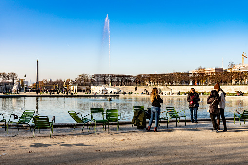 2019 Pathway in Jardin des Tuileries. Paris, France. In the foreground are tourists around the fountain.