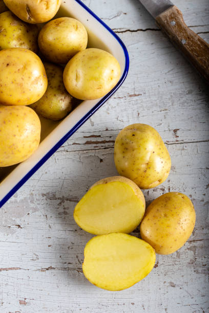 istock Raw potatoes in wooden bowl on black background 1197302736