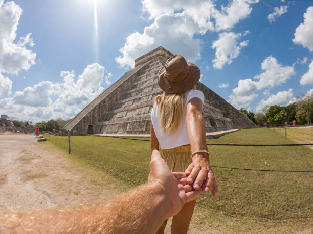Follow me to the Mayan ruins in Mexico; Girl leading boyfriend to Mexican temple Follow me to the Mayan ruins in Mexico; Woman tourist leading boyfriend to the old pyramid; People travel concept chichen itza stock pictures, royalty-free photos & images