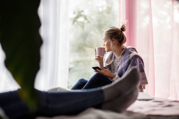 istock Candid low angle view of girl drinking beverage by the window 1197304194