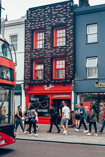 London/UK - July 17, 2019: people walking past the Ray-Ban shop on Camden High Street in Camden Town. Ray-Ban is an American-founded Italian brand of luxury sunglasses and eyeglasses created in 1936