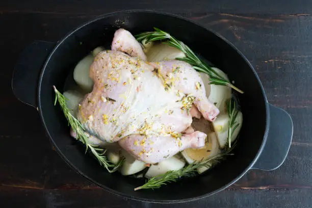 Chicken, onions, and rosemary seasoned and prepared to roast in a cast-iron pot