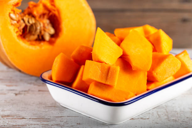 istock Peeled and chopped pumpkin on wooden background. 1197308452