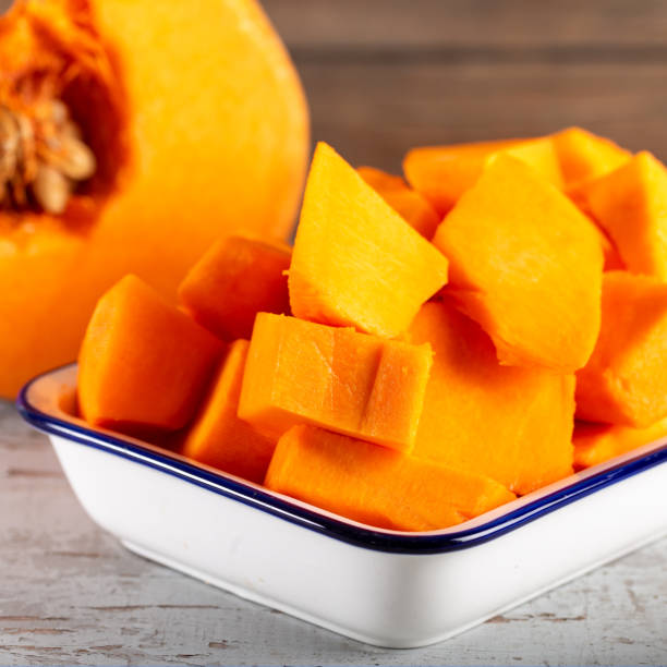 istock Peeled and chopped pumpkin on wooden background. 1197308982