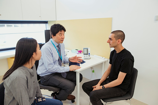A side-view shot of a doctor discussing a patient's blood pressure.