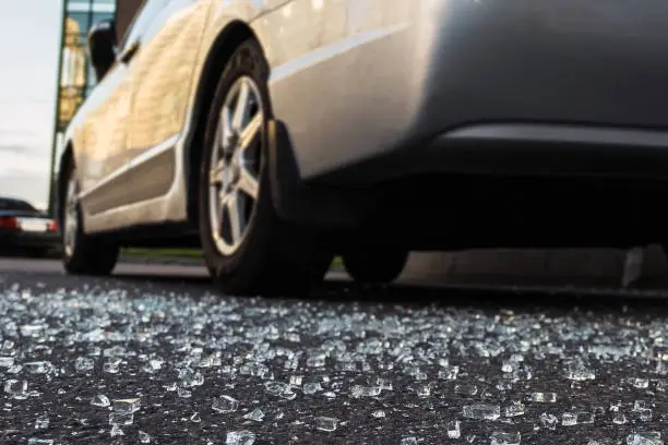 Glass fragments scattered on asphalt from broken car glass, concept of vandalism