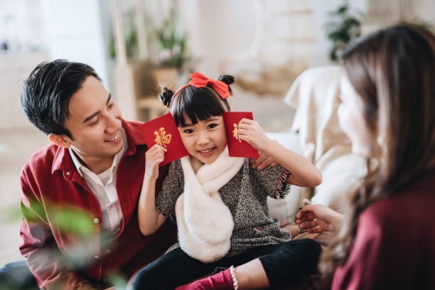 Lovely daughter happily received red envelops (lai see) from her parents in Chinese New Year Lovely daughter happily received red envelops (lai see) from her parents in Chinese New Year family reunion celebration stock pictures, royalty-free photos & images