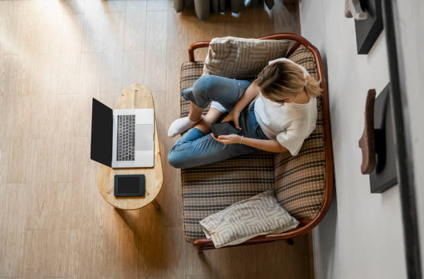 istock Woman use a smartphone while lying on a sofa with a laptop and ereader on a table. Studying online, freelance. Self employed or freelance girl use a phone and resting from work whith a notebook. 1197326042