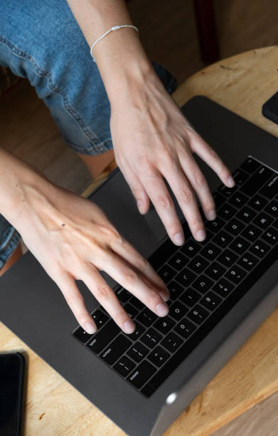 Woman is sitting on a sofa and using a laptop at wooden table. Study and work online, freelance. Self employed girl is working with her notebook sitting on a couch with a phone and ereader on table la mujer está sentada en un sofá y usada un ordenador portátil en una mesa de madera. estudiar y trabajar en línea, freelance. la chica autoempleada está trabajando con su cuaderno sentado en un sofá con un teléfono y un ereader en la mesa.