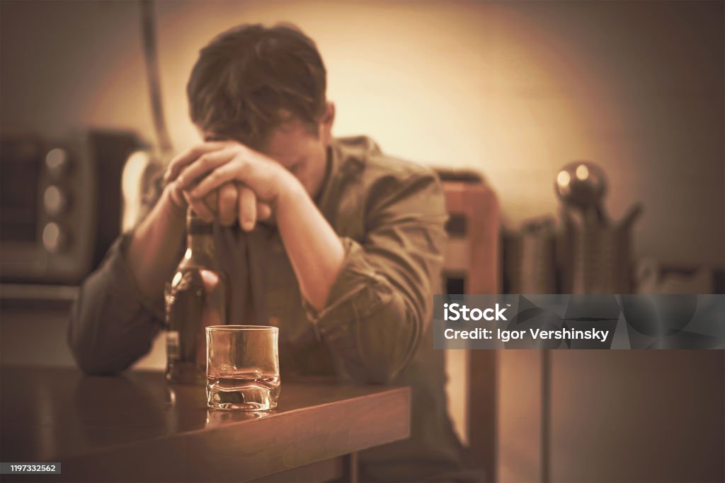 The problem of family drinking A man with bottle of whiskey on the kitchen. The concept of drunkenness and alcoholism. Alcoholic father.    Toning. Alcohol Abuse Stock Photo