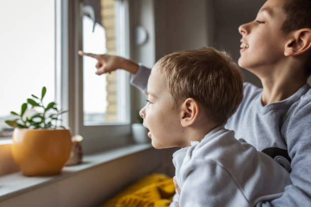Two brothers looking through the window on cold winter day