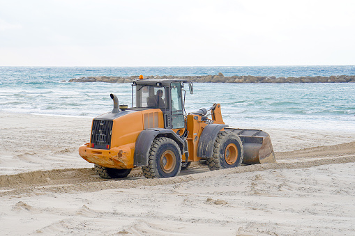 A bulldozer and a panoramic view of the sea in Tel Aviv, Israel. Yellow bulldozer in front of the sea.