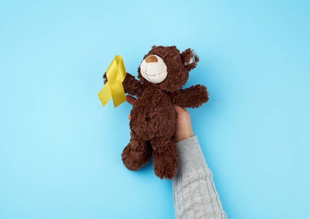 istock small brown teddy bear which holds in its paw a yellow ribbon folded in a loop 1197336063