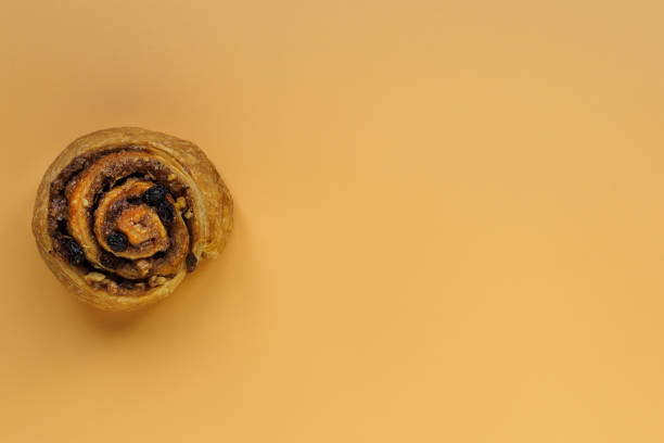istock Cinnamon, nut and raisin bun on orange background with copy space 1197340783
