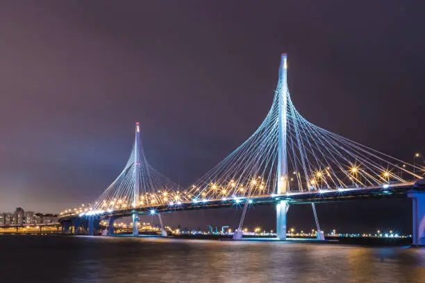 Photo of The bridge of circle highway road over Neva river near the mouth of it in the night. Night view on the buildings of Petersburg city and the Finish gulf