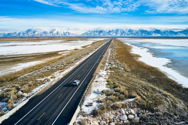 A car driving on a long causeway road in the winter.