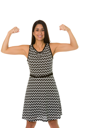 Three fourths body shot of a Hispanic businesswoman flexing her muscles to show her strength. Isolated on white