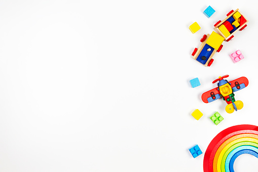 Baby kids toys background. Wooden train, red plane, stacking rings rainbow toy and colorful blocks. Top view