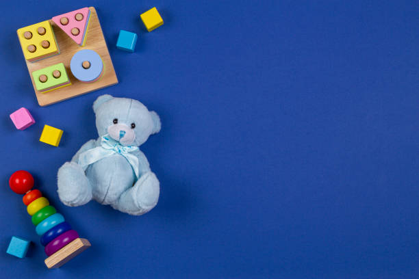 istock Baby kids toys background. Blue teddy bear, stacking pyramid tower, shape color recognition puzzle stacker and colorful blocks on navy blue background. Top view 1197351761