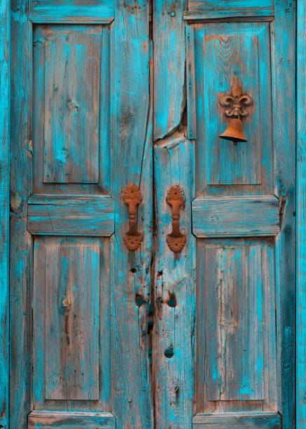 istock Splintered and peeling turquoise door with rusted bell 1197352931