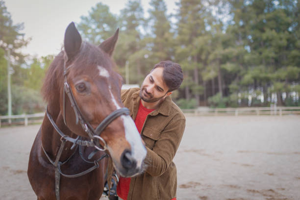 istock a young man walking with a brown horse 1197358327