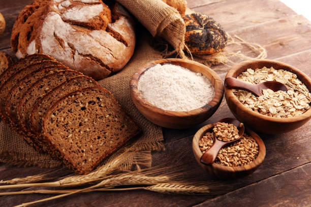 istock Assortment of baked bread and bread rolls and cutted bread on table background 1197361538