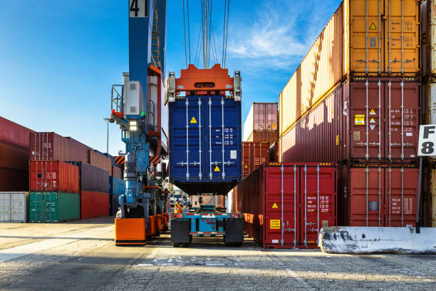 Rear View of Straddle Carrier Lifting Container from Truck Shot of an intermodal shipping yard in the Port of Long Beach, California. pier stock pictures, royalty-free photos & images