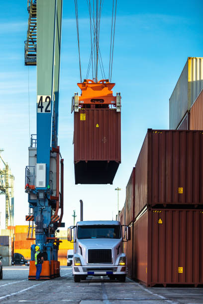 Straddle Carrier Lifting Cargo Container from Truck Shot of an intermodal shipping yard in the Port of Long Beach, California. long beach california photos stock pictures, royalty-free photos & images