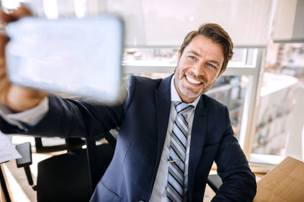 istock Businessman in office taking selfie with his smart phone 1197368708