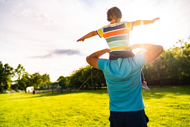 istock Rear view small boy sitting on men shoulders 1197371704