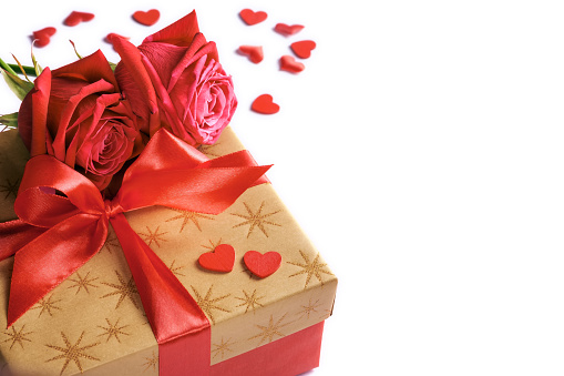 Golden gift box with red ribbon, roses and little hearts isolated on white, concept of Valentine's day, anniversary, mother's day or birthday greeting, copy space, closeup view.