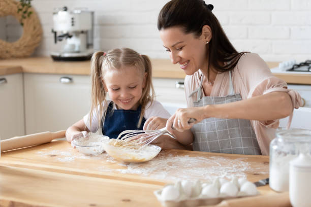 istock Young mommy showing small daughter how to stir eggs. 1197373135