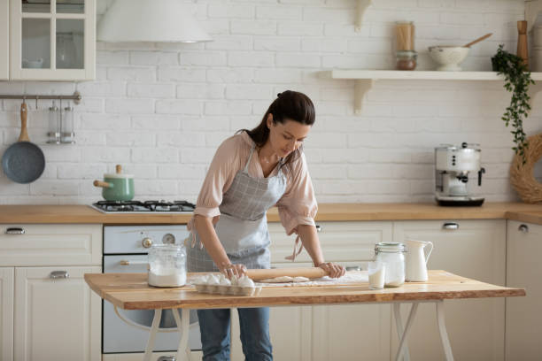 istock 30s woman leaning over table, rolling out dough. 1197373142