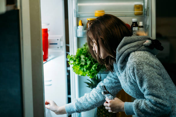 istock Young girl at night in front of a refrigerator 1197373348