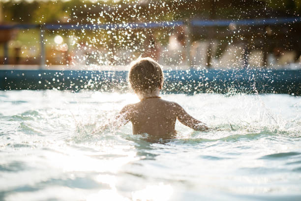 istock Rear view small boy sitting in pool and splashing 1197374223