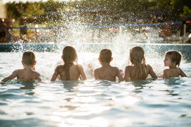 istock Rear view kids enjoying splashing in the pool 1197375912