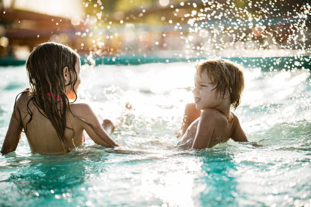 istock Side view small boy and girl splashing in the pool 1197376257
