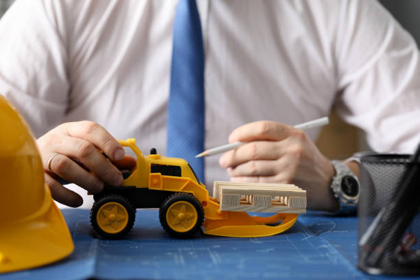 istock Male constructor hand hold yellow tractor against 1197388073