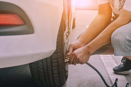 People inflating the tires of car parked