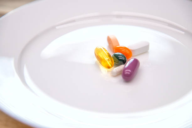 A white dinner plate of colorful dietary supplements symbolizing society's willingness to replace eating meals with taking supplements.