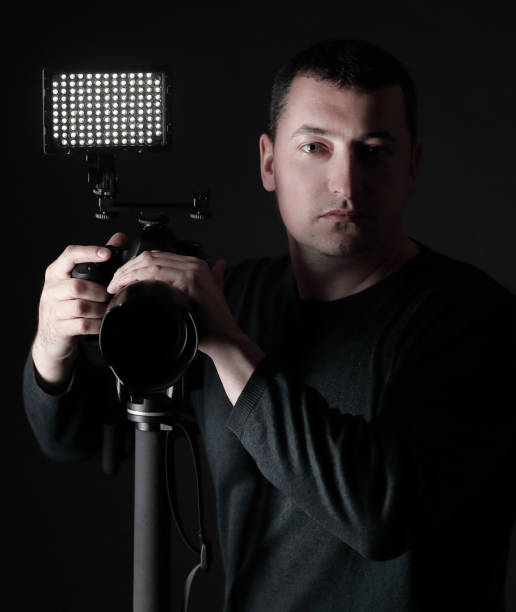 istock professional photographer with camera on tripod.isolated on black background 1197406382