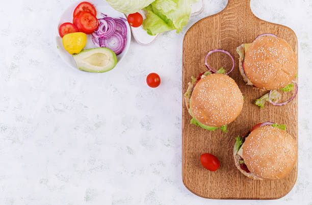 istock Big sandwich - hamburger burger with beef, avocado, tomato and red onions on light background. American cuisine. Fast Food. Top view, overhead 1197425475