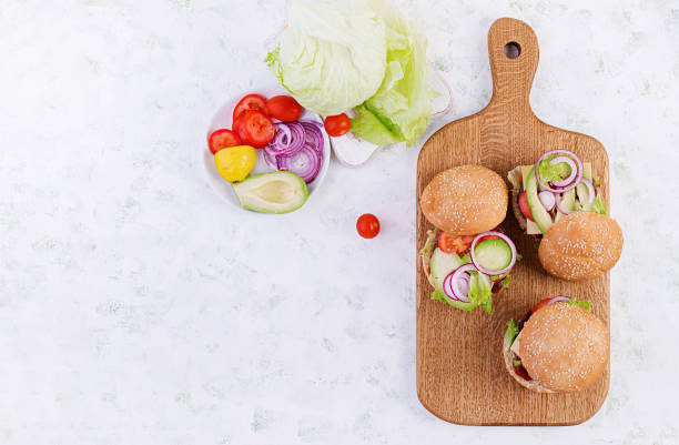 istock Big sandwich - hamburger burger with beef, avocado, tomato and red onions on light background. American cuisine. Fast Food. Top view, overhead 1197425477