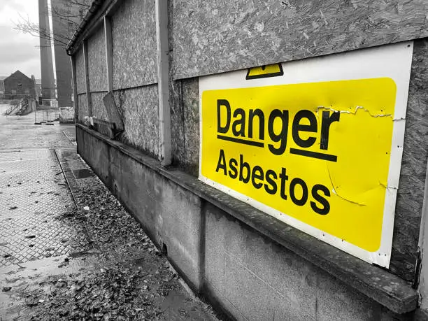 Asbestos danger sign at building construction site refurbishment of old building uk