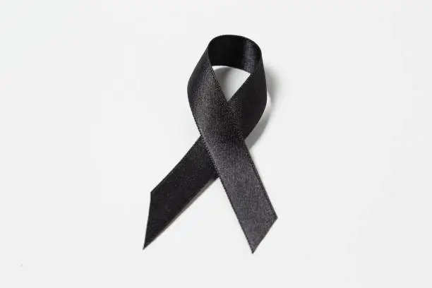 Black awareness ribbon on white background. Symbol for mourning, with copy space.