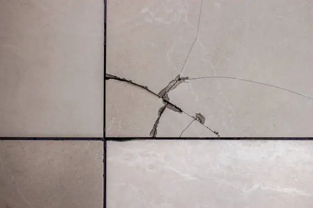 Photo of Cracked tile. Broken tile on the floor.