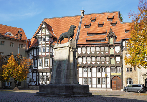 Braunschweig, Germany - October 15, 2019: Brunswick Lion monument located on historic Burgplatz castle square with timber-framed houses in the background.