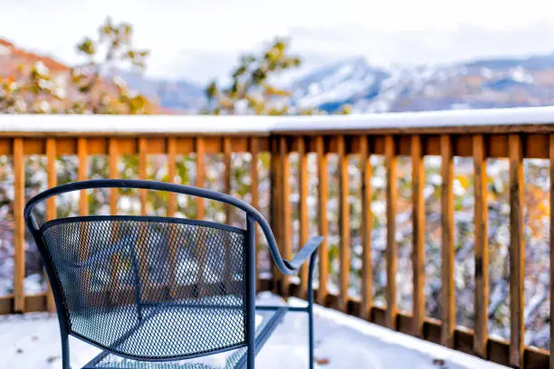Wooden railing of deck balcony terrace and metal chair in garden outside in Aspen, Colorado view of rocky mountains and snow covered weather