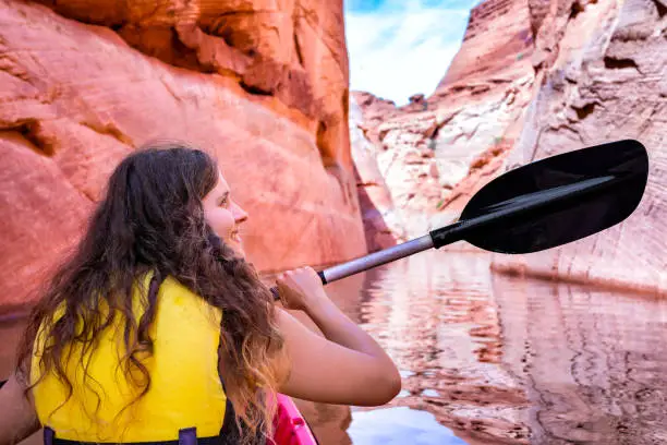 Back of young happy girl kayaking on lake powell with paddle and kayak and life vest on Antelope slot canyon in Arizona during summer