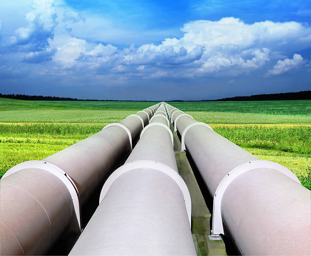 Three gas pipelines in a green field with blue sky stock photo
